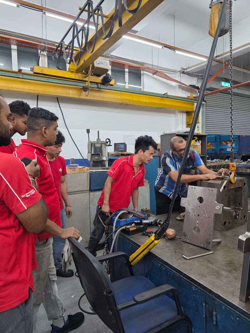 Trainer demonstrating chain and hook inspection to factory workers