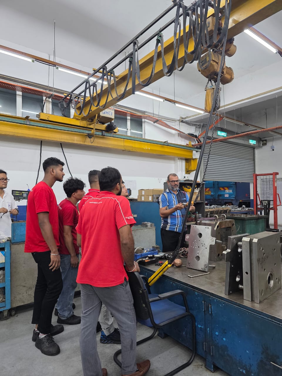 Workers observing overhead crane safety demonstration